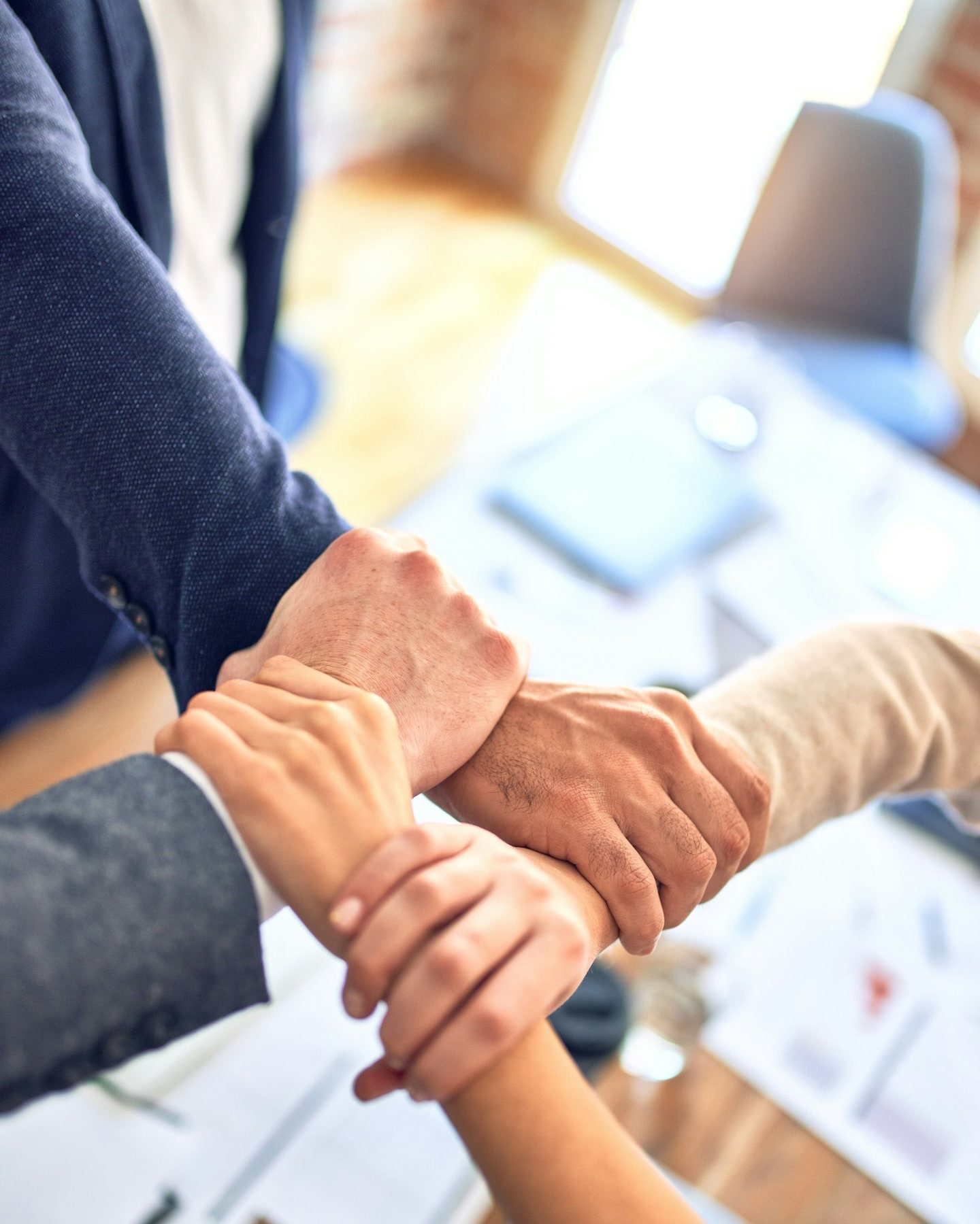 A team joining hands across a meeting table