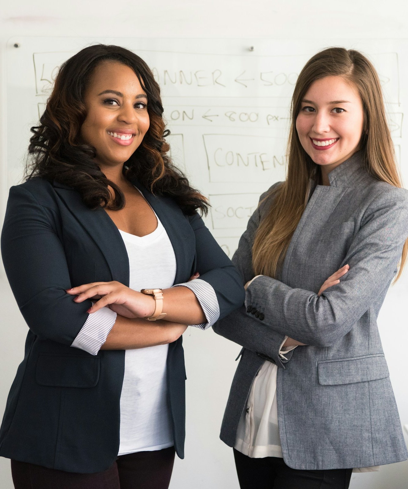 Two confident professionals in blazers standing in a modern office